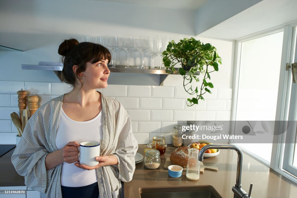 Woman with hot drink in zero waste kitchen.