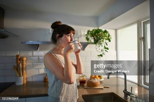 woman drinking from mug in zero waste kitchen. - beschaulichkeit stock-fotos und bilder