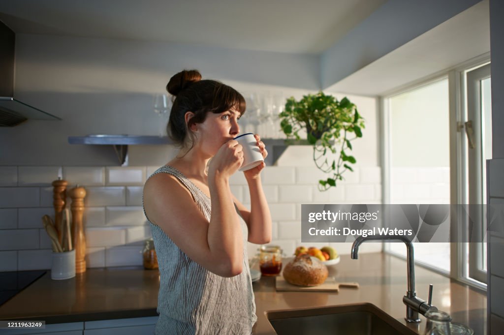 Woman drinking from mug in zero waste kitchen.