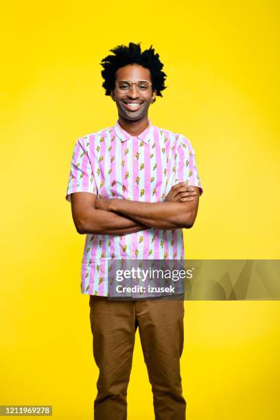 freundlicher junger mann trägt vintage-shirt, porträt auf gelbem hintergrund - multi coloured shirt stock-fotos und bilder