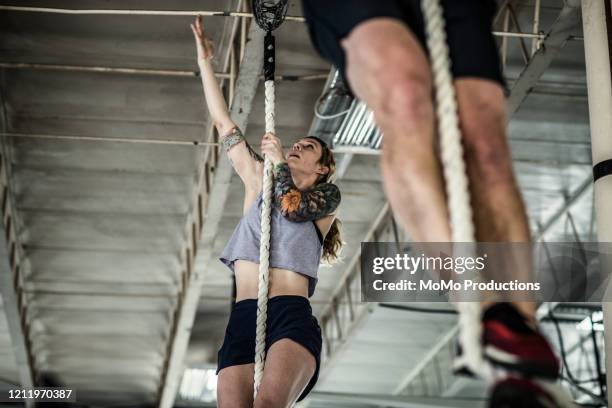 woman using climbing rope at cross training gym - woman climbing rope stock-fotos und bilder