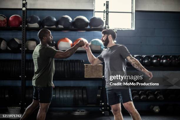 men fist-bumping after cross training class - prop sporting position stock pictures, royalty-free photos & images