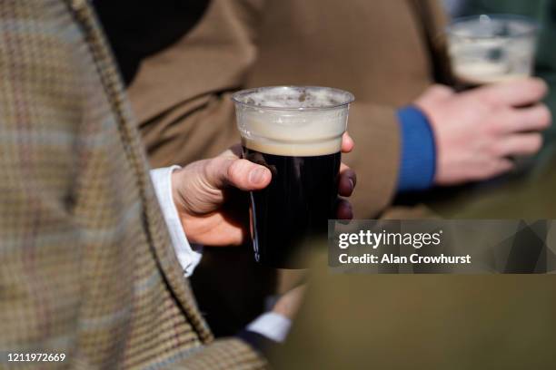 Racegoers hold pints of Guinness in the Guinness Village at Cheltenham Racecourse on March 12, 2020 in Cheltenham, England.