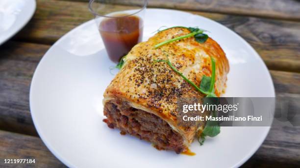 plate of vegan sausage roll pastry snack on a wooden surface - sausage roll stock pictures, royalty-free photos & images