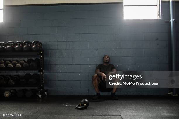 man resting against wall at cross training gym - running shorts stock pictures, royalty-free photos & images