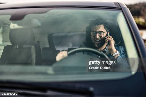 frustrated man driving and talking on phone. - distracted driver stock pictures, royalty-free photos & images