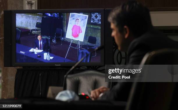 Senator Richard Blumenthal is seen on a video monitor questioning Judge Justin Walker, while Blumenthal displays a photo of a young constituent from...