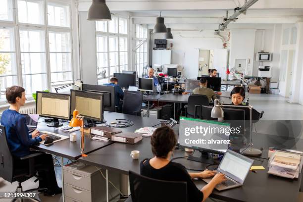 geschäftsleute, die in einem großraumbüro arbeiten - open laptop on desk stock-fotos und bilder