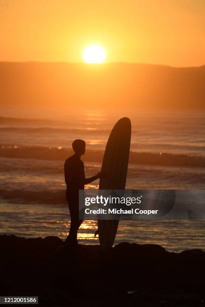 Surfer looks out to sea at sunset on a deserted Castlerock Beach, Co Londonderry on May 6, 2020 in Castlerock, Northern Ireland. The UK is continuing...