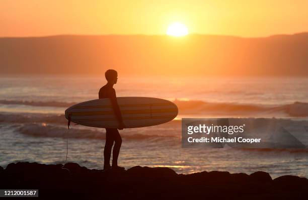 Surfer looks out to sea at sunset on a deserted Castlerock Beach, Co Londonderry on May 6, 2020 in Castlerock, Northern Ireland. The UK is continuing...