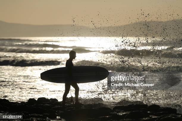 Surfer looks out to sea at sunset on a deserted Castlerock Beach, Co Londonderry on May 6, 2020 in Castlerock, Northern Ireland. The UK is continuing...