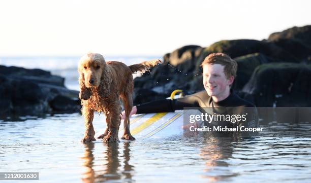 Surfer plays with his dog on a deserted Castlerock Beach, Co Londonderry on May 6, 2020 in Castlerock, Northern Ireland. The UK is continuing with...