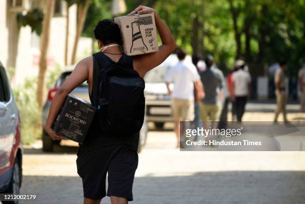 Man carries carton of alcohol bottles outside a liquor shop at Sector 40, near Huda Market during lockdown 3.0 to curb the spread of Coronavirus...