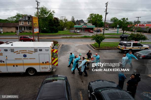 Firefighters and paramedics with Anne Arundel County Fire Department wear enhanced PPE, during the coronavirus pandemic, as they transport a patient...