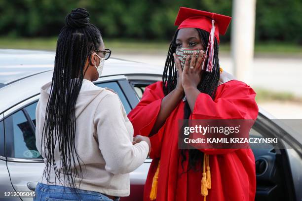Graduate student Tyleah Whitlow puts a mask on her face as she arrives to pick up her diploma at Bradley-Bourbonnais Community High School on May 6,...