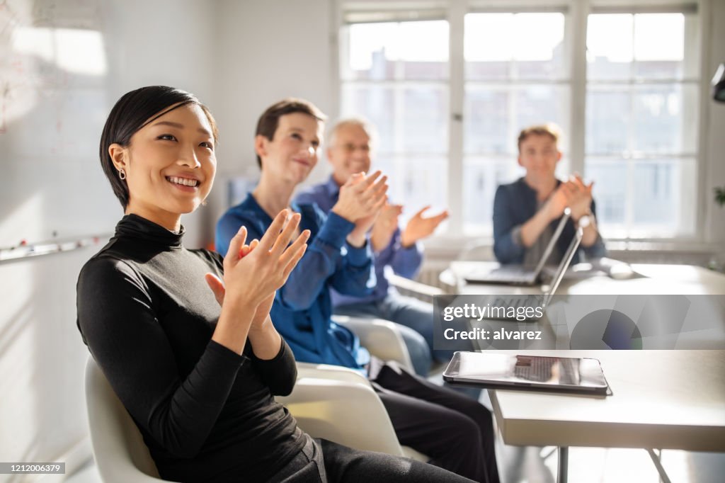 Business professionals clapping hands in a meeting