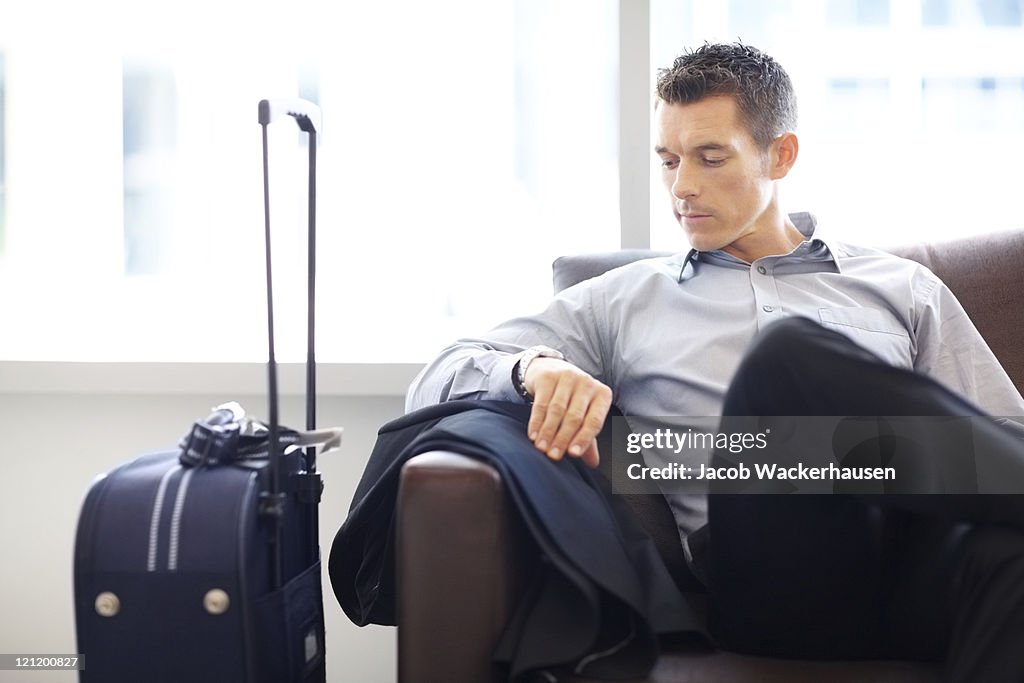 Young business man at the airport lounge checking time