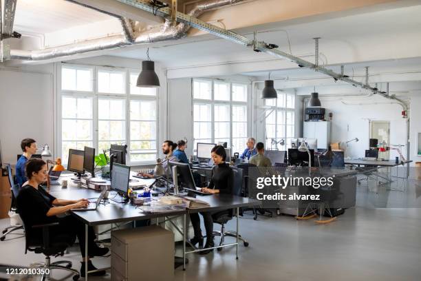 beschäftigt modernes großraumbüro mit mitarbeitern - office interiors stock-fotos und bilder