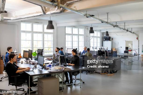 affollato ufficio moderno a pianta aperta con personale - dipendente foto e immagini stock