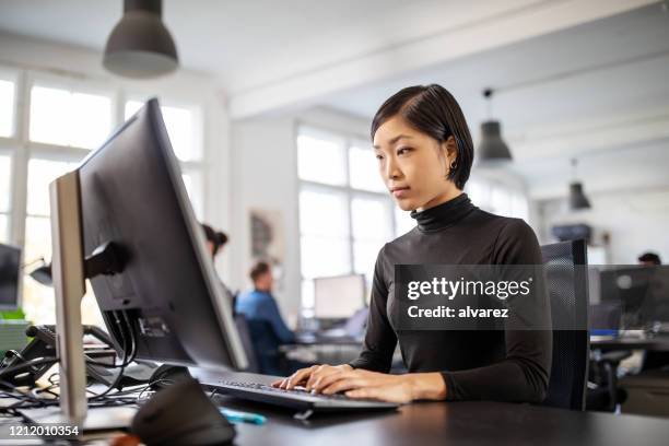 frau beschäftigt arbeiten an ihrem schreibtisch in offenen büro - workstation stock-fotos und bilder