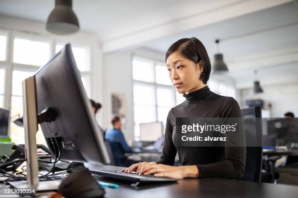 vrouw bezig die bij haar bureau in open planbureau werkt - pc woman stockfoto's en -beelden