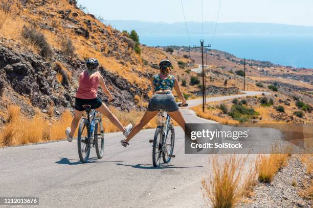 vrouwen die onderaan landweg op fietsen free wheeling - kreta stockfoto's en -beelden