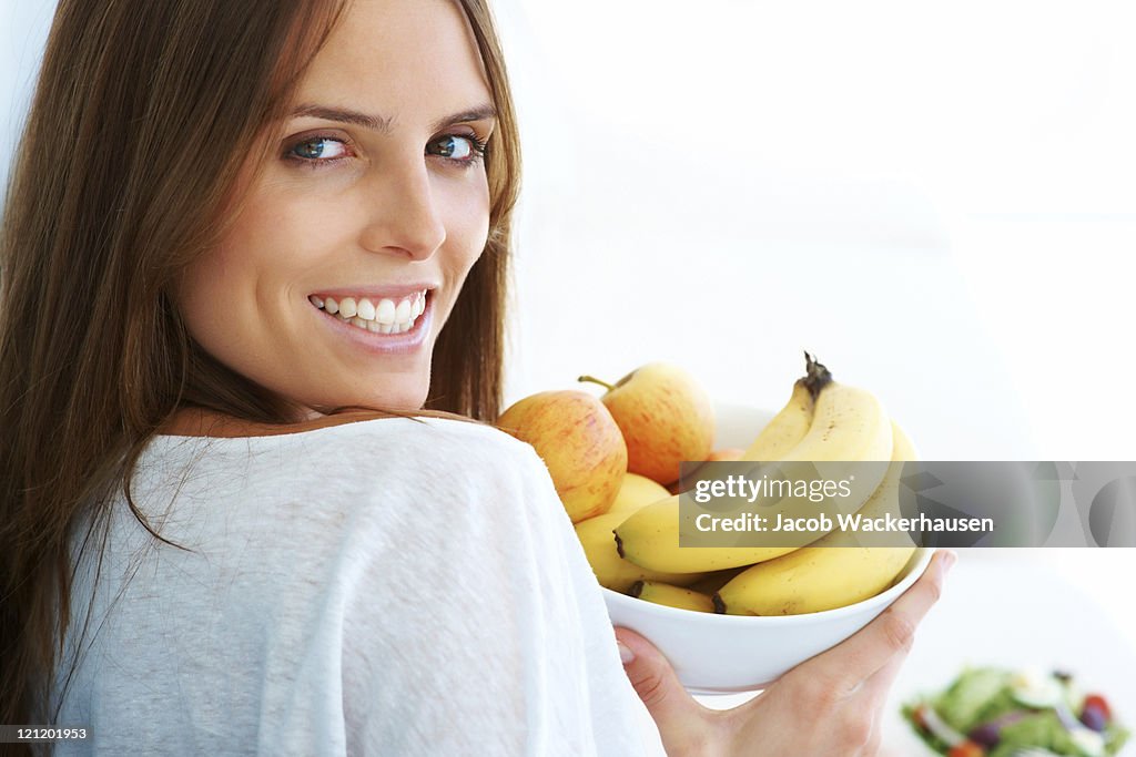 Young woman holding a bowl of fruit