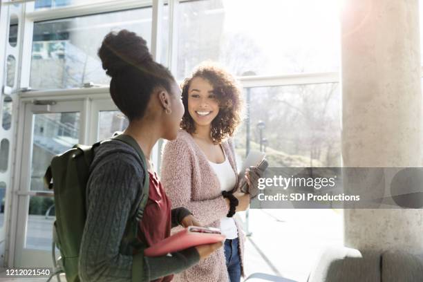 attentive female student talks with friend - college students stock pictures, royalty-free photos & images