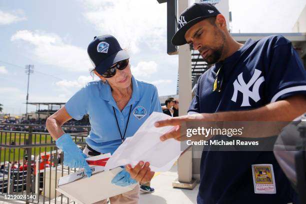 Usher, wearing protective gloves, helps a fan find their seat prior to a Grapefruit League spring training game between the Washington Nationals and...