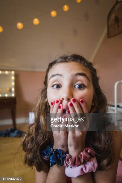 portrait of surprised girl covering face while vlogging in bedroom at home - hands covering mouth stockfoto's en -beelden