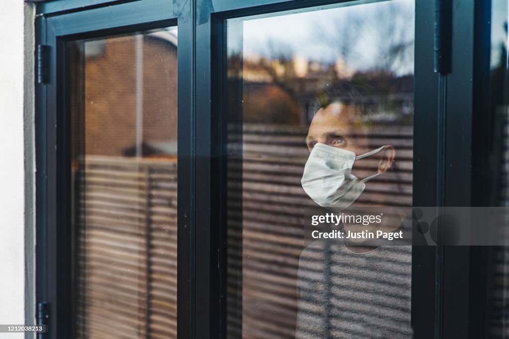 Man with mask looking out of window