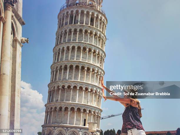 teen girl with a hat taking the typical tourist photo holding the leaning tower of pisa in italy - torre de pisa imagens e fotografias de stock