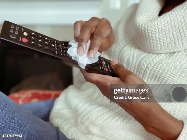 woman cleans remote control using disinfectant wipe - wet jeans stock-fotos und bilder