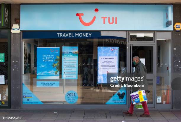 Pedestrian wearing a protective face mask passes an electronic advertising screen inside a closed travel agency store, operated by Tui AG, in Harlow,...