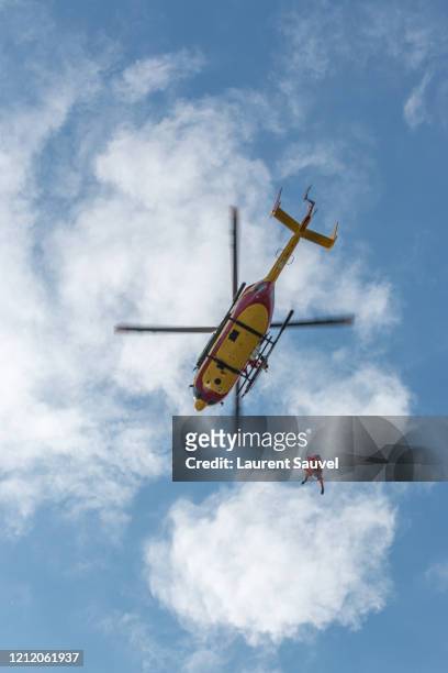low angle view of a helicopter rescue against a cloudy clear blue sky - laurent sauvel photos et images de collection
