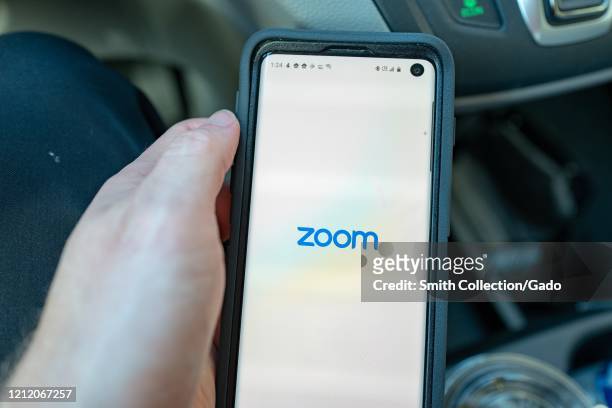 Close-up of hand of a man holding a Samsung Galaxy S10 smartphone with app for teleworking and conference call company Zoom, Walnut Creek,...