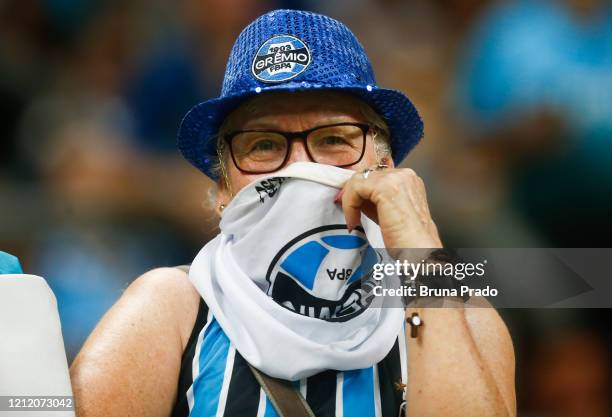 Fan covers her mouth with a Gremio flag to take precautions against the spread of the Coronavirus before the match against Internacional for the Copa...