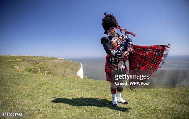 Pipe major Andy Reid of The Scots Guards plays his pipes on the cliffs of Dover as two Spitfires from the battle of Britain memorial flight fly over...