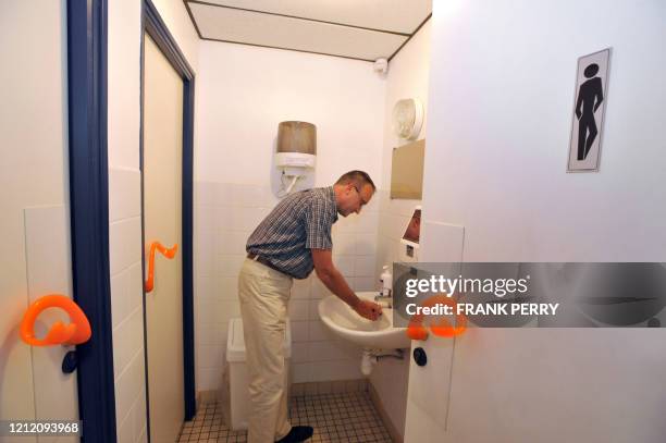 La grippe fait exploser les ventes d'une poignée de porte +anticontamination+" - A man washs his hands in toilets kiped out by the first ergonomic...