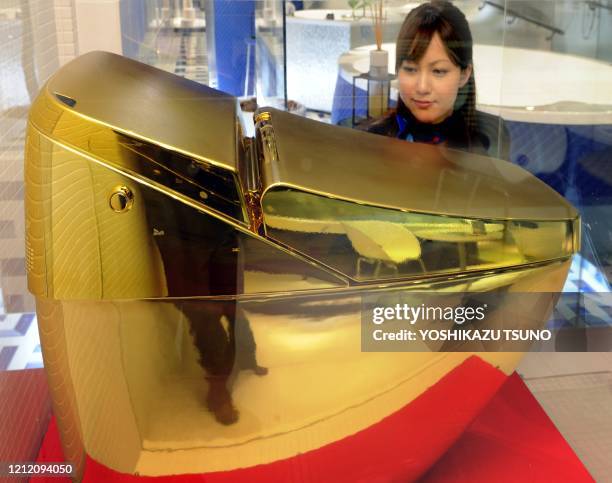 An employee of Inax, a tiling and sanitary fixtures manufacturer displays the company's flagship toilet "Regio" with a special gold glaze, at Inax's...