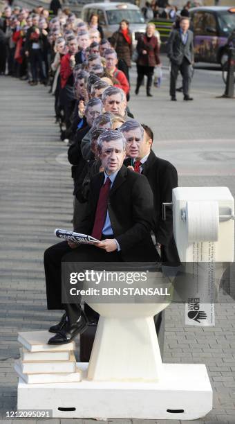 Protestors wearing masks depicting British Prime Minister Gordon Brown queue in front of a giant toilet outside the Houses of Parliament in London,...