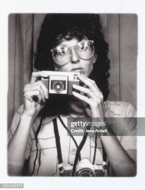 retro 1980s woman with retro eyeglasses holding camera - 80s hair fashion stock-fotos und bilder