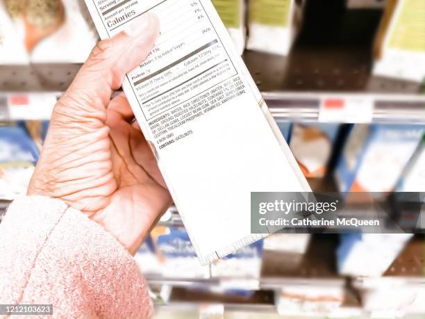 african-american woman reads nutrition label at grocery store - fda stock pictures, royalty-free photos & images