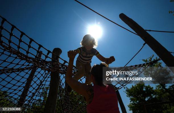 Mother takes her son from a climbing frame at a playground at the Zoom Erlebniswelt zoo as it reopens for the public in Gelsenkirchen on May 7, 2020...