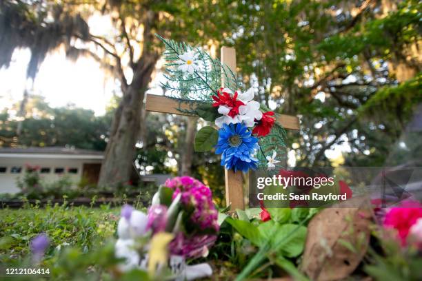 Cross with flowers sits near the intersection of Satilla Rd. And Holmes Rd. In the Satilla Shores neighborhood where Ahmaud Arbery was shot and...
