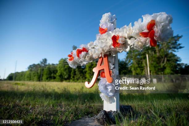 Cross with flowers and a letter A sits at the entrance to the Satilla Shores neighborhood where Ahmaud Arbery was shot and killed May 7, 2020 in...