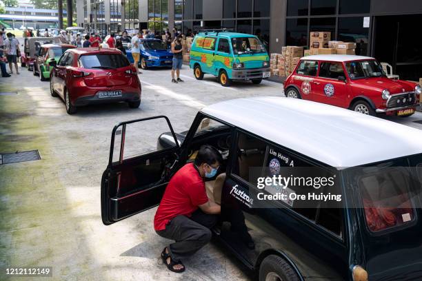 Volunteers from the Mini Classic Car Club get ready to move off after their car is loaded with packed items to be distributed to migrant workers on...