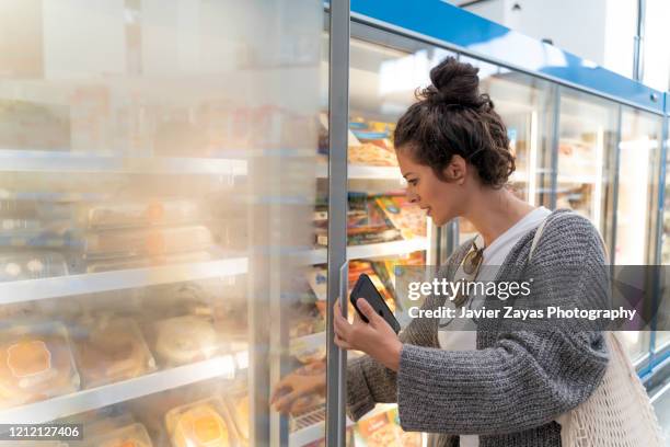 young women in supermarket grocery shopping - comida congelada fotografías e imágenes de stock