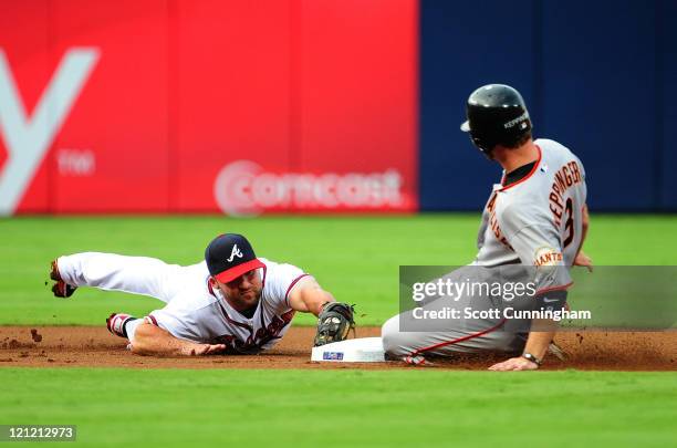 Jeff Keppinger of the San Francisco Giants slides safely in to second base against Dan Uggla of the Atlanta Braves at Turner Field on August 15, 2011...