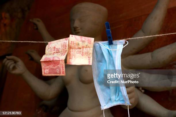 Indian rupee and a surgical mask dry in the sun after disinfection at a workshop area amid the ongoing coronavirus lockdown in Kolkata, India, 07 May...